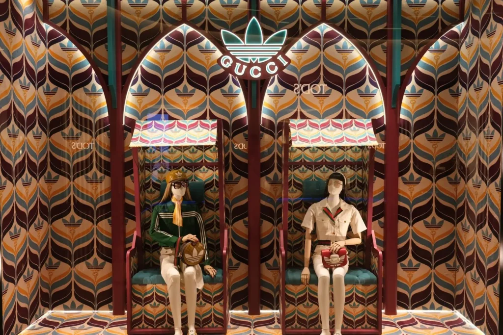 Campaign section image from the collaboration between adidas and gucci, featuring mannequins sitting in front of a patterned background.