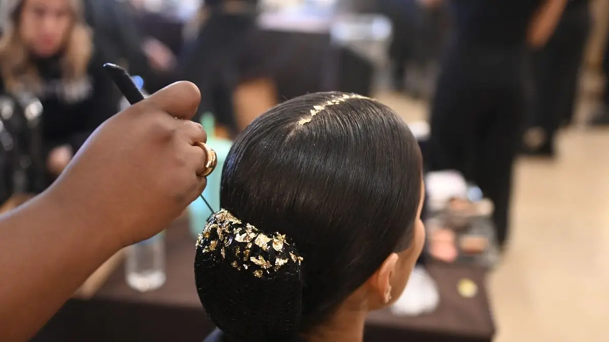 Gold plated hair accessories being applied on a model for Christian Siriano