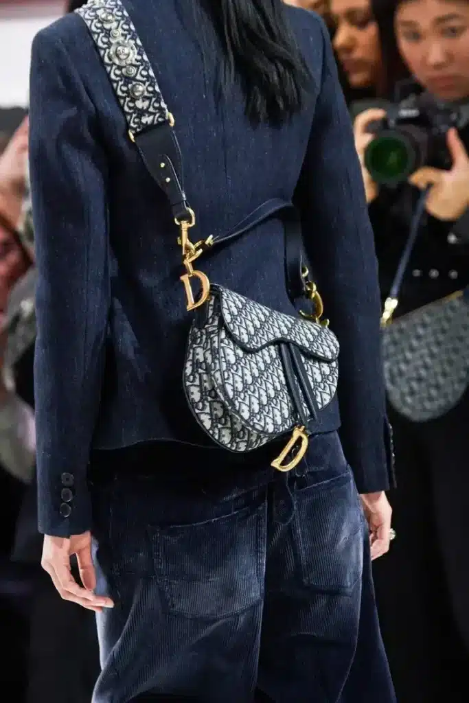 Dior model wearing blue, carrying a matching dior saddle bag