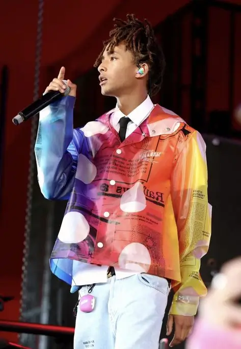 Jaden wearing a regular white shirt with black tie but switching things up with a polka dot, fluorescent, translucent jacket on top