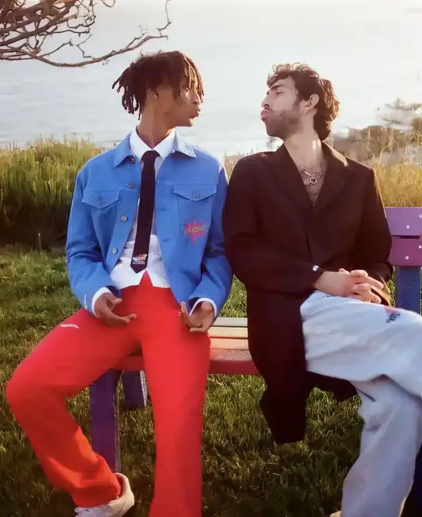 jaden wearing a white shirt black tie, red pants and blue jacket