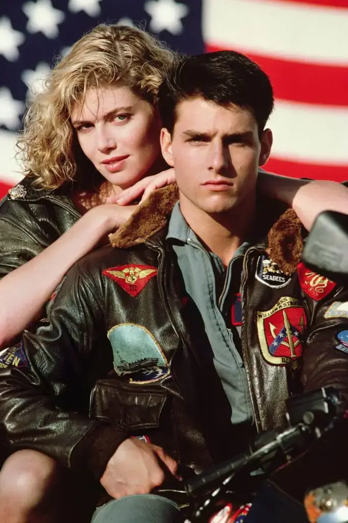 movie screenshot of tom cruise wearing his iconic leather jacket with patches from "Top Gun"