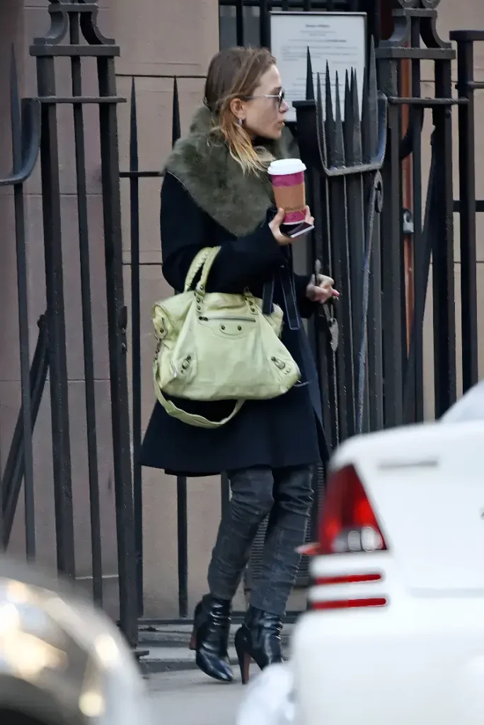 Image of Mary Kate Olsen standing outside carrying a green balenciaga classic city bag.