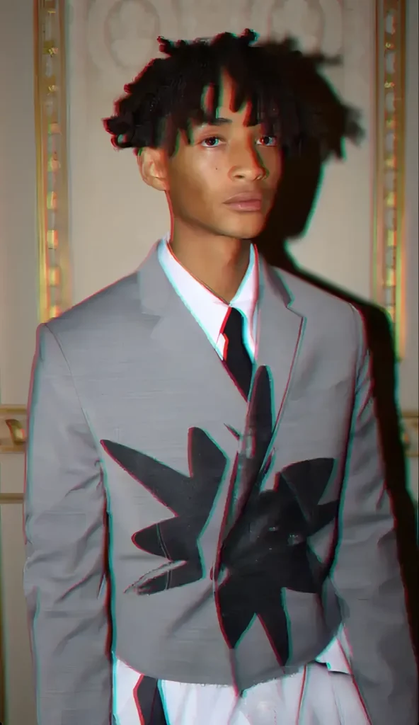 jaden wearing white shirt and black tie with cropped grey blazer with a graphic on it