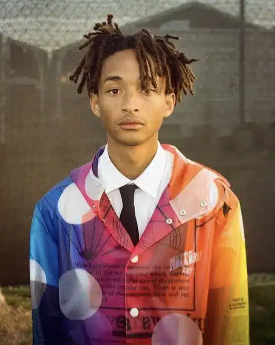 Jaden wearing a regular white shirt with black tie but switching things up with a polka dot, fluorescent, translucent jacket on top