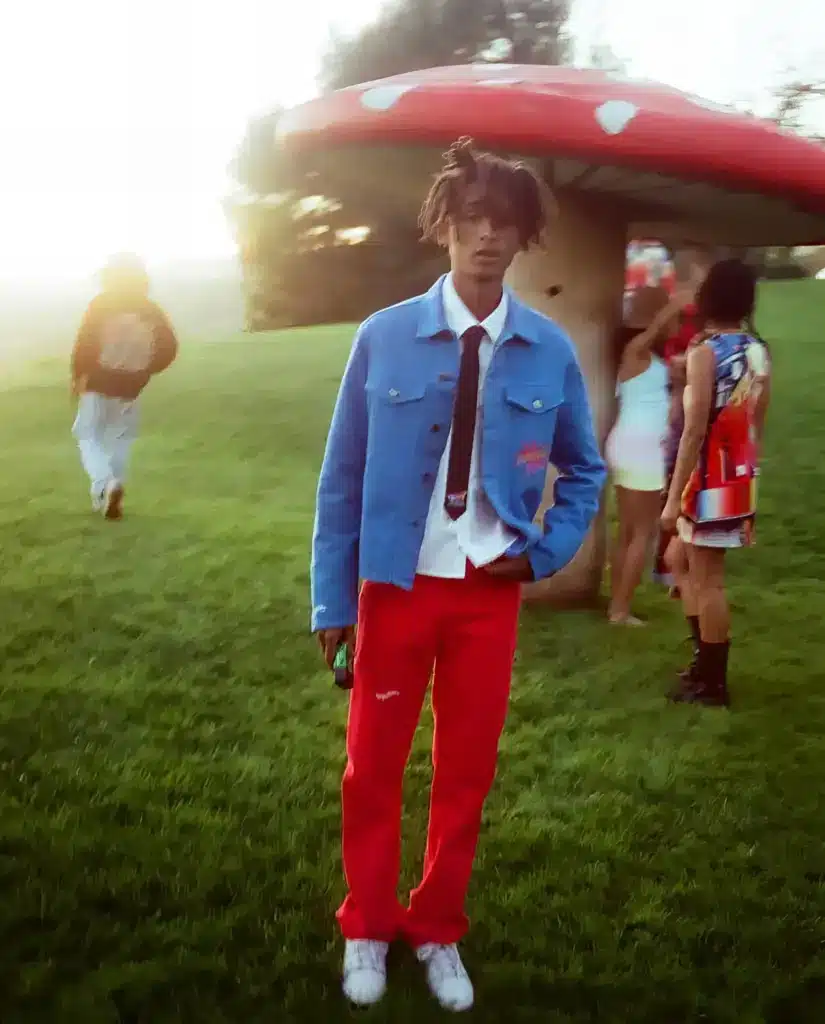 jaden wearing a white shirt black tie, red pants and blue jacket