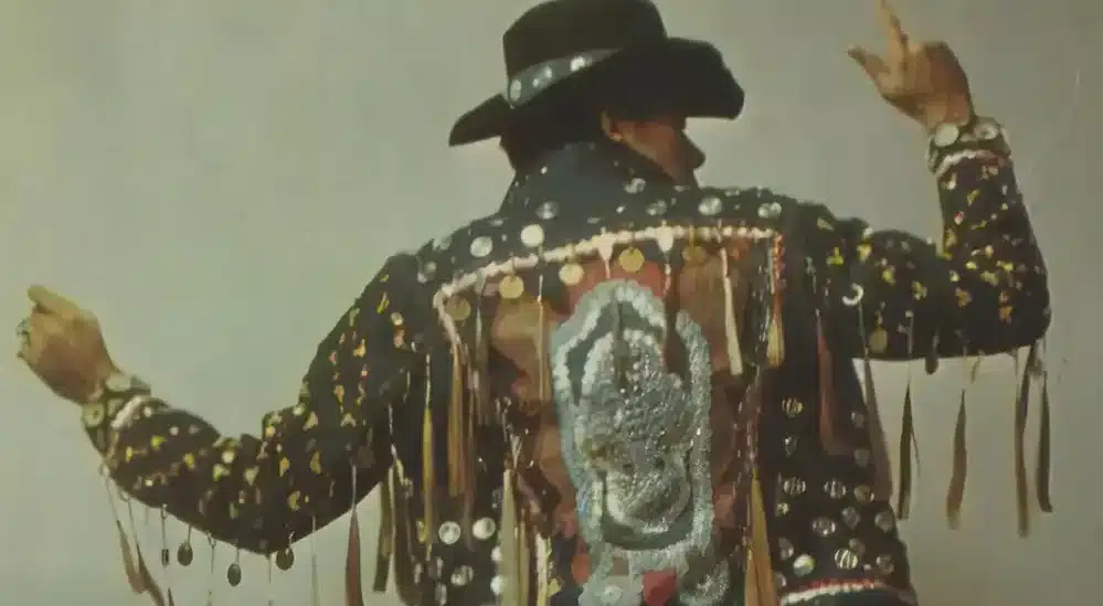 the back of a dancing cowboy showing off this stylish jacket adorned with decorations and cowboy hat