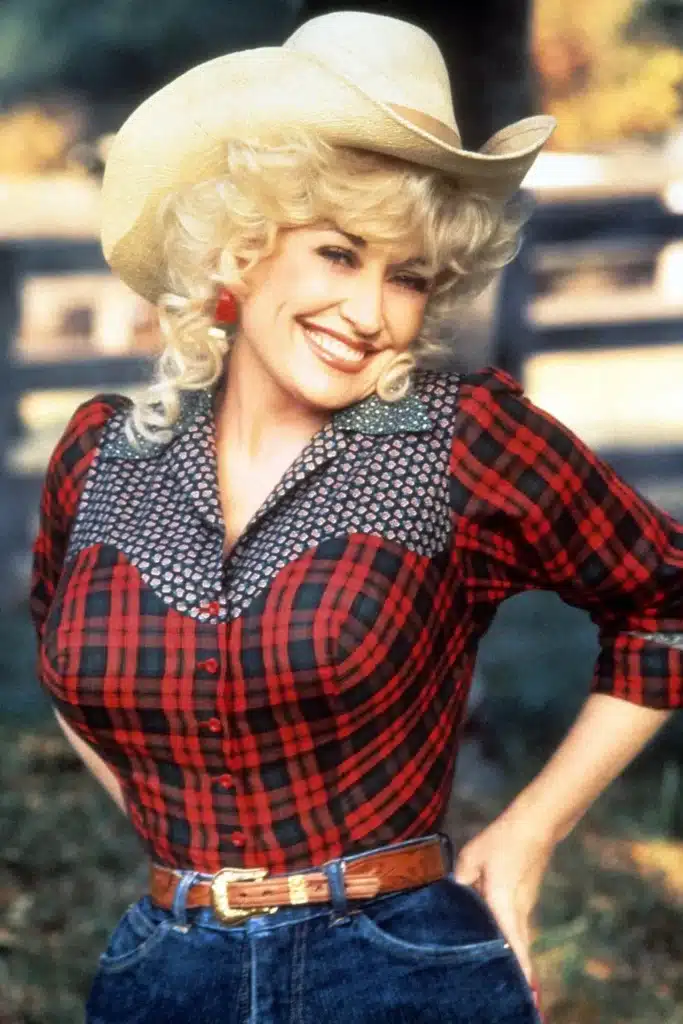 Dolly Parton vintage western fashion, wearing a white cowboy hat, plaid top and blue denim jeans