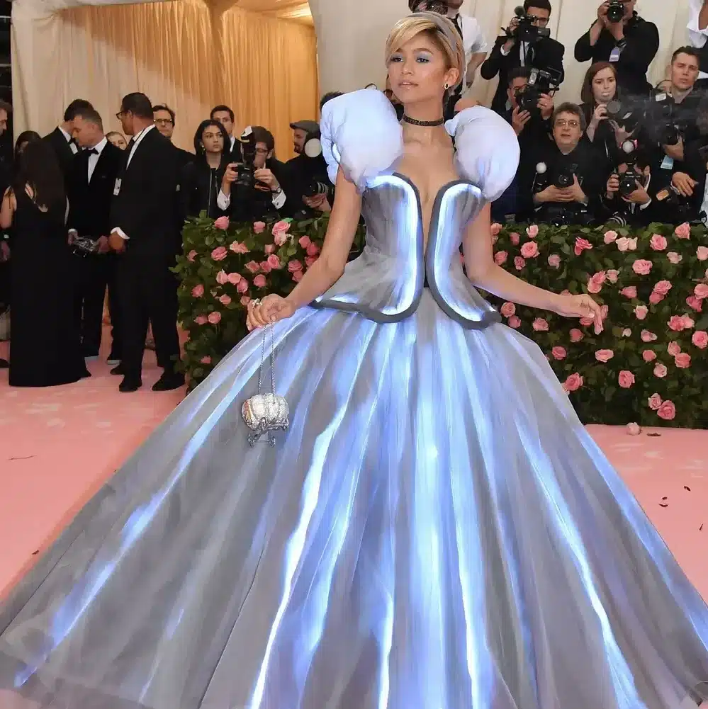 Zendaya wearing a grey and blue color shape shifting cinderella inspired outfit, made by Tommy Hilfiger for the 2019 met gala