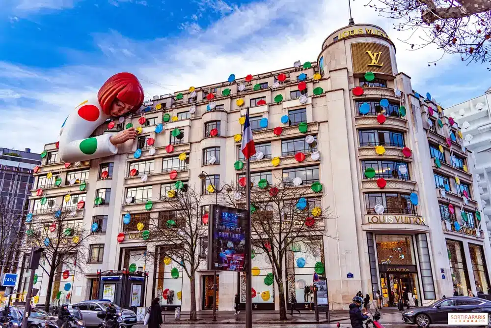 The Louis Vuitton store on Champs-Élysées in Paris, adorned with colorful polka dots and a large installation of Yayoi Kusama's iconic character, showcasing the playful and artistic collaboration between the fashion house and the renowned artist.