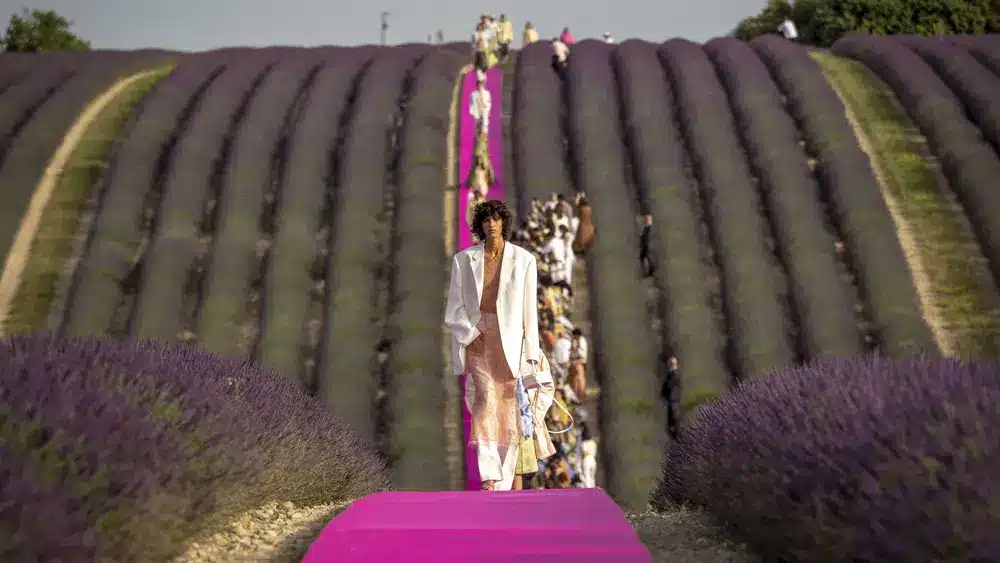 Models walking on a pink runway through lavender fields during Jacquemus's 10th anniversary show, showcasing the brand's picturesque and serene show settings.