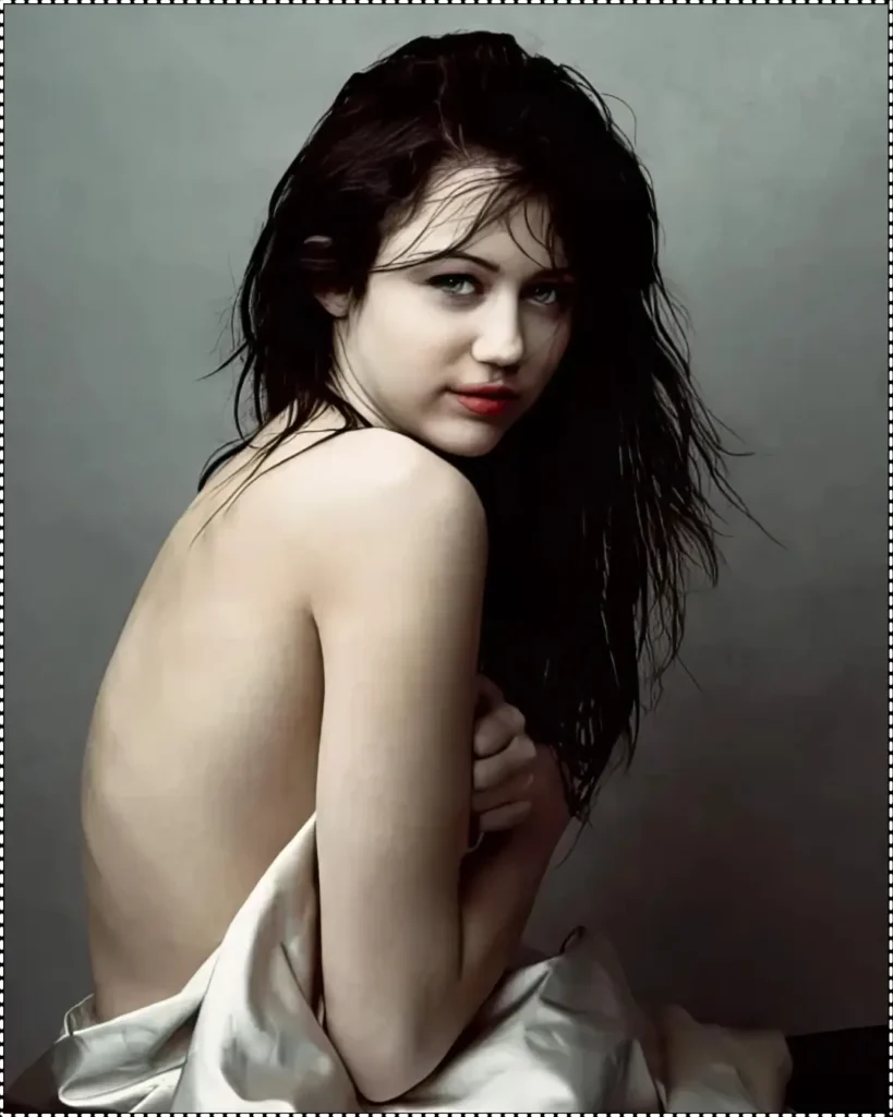 An intimate portrait by Annie Leibovitz of Miley Cyrus with dark, wet hair, wrapped in a white sheet, looking over her shoulder with a natural expression and minimal makeup.