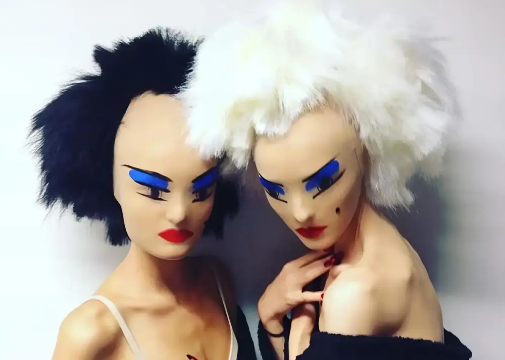 Two models wearing Gareth Pugh's designs, featuring exaggerated makeup and avant-garde masks, highlighting the futuristic and bold aesthetic of the collection.