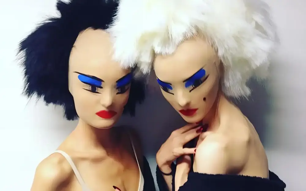 Two models wearing Gareth Pugh's designs, featuring exaggerated makeup and avant-garde masks, highlighting the futuristic and bold aesthetic of the collection.